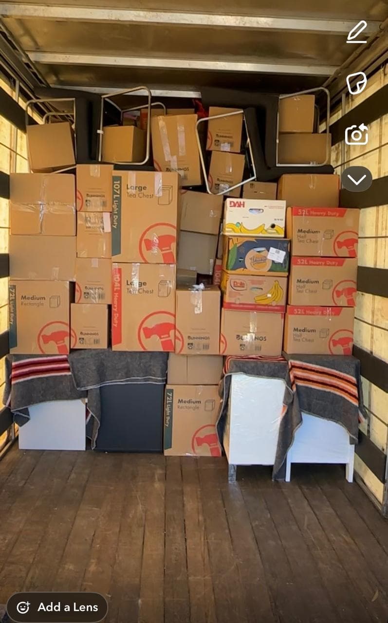 Moving boxes stacked above blanket-protected furniture